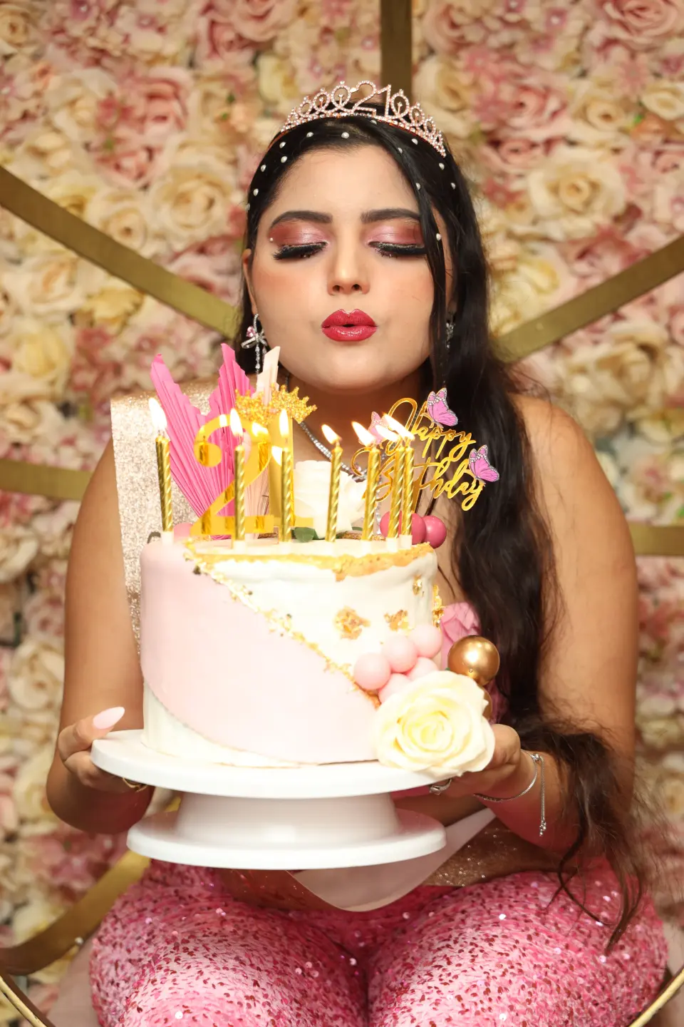 Jeune femme soufflant un baiser derrière son gâteau d’anniversaire, décor floral