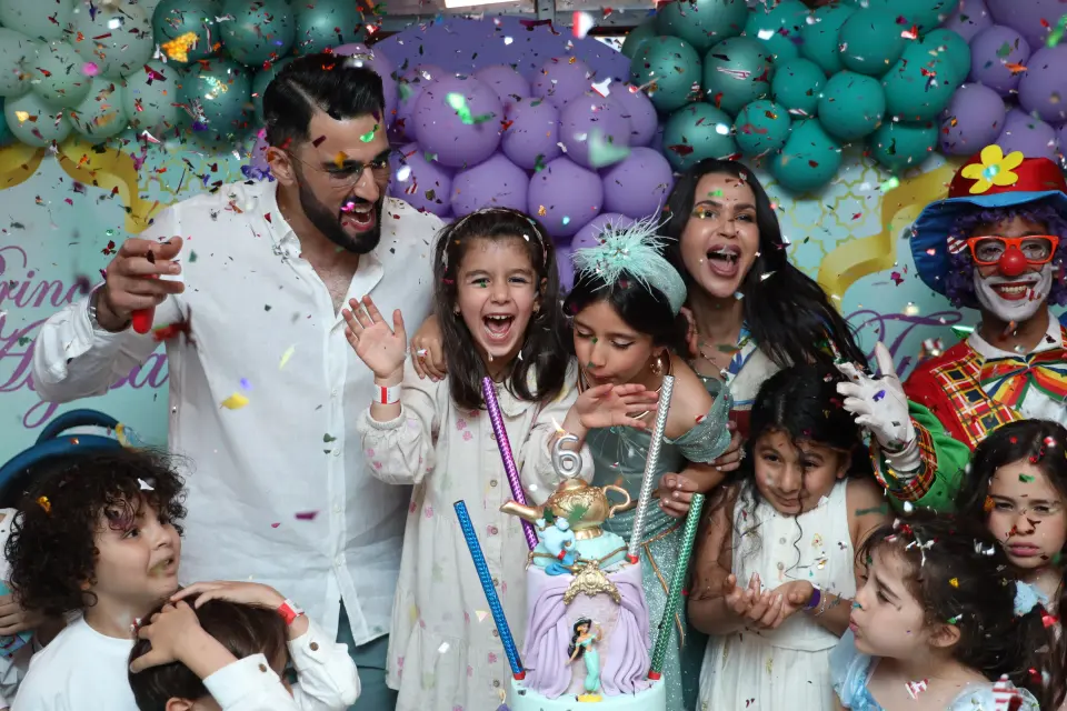 Famille et enfants réunis autour du gâteau lors d’une fête d’anniversaire décorée de ballons