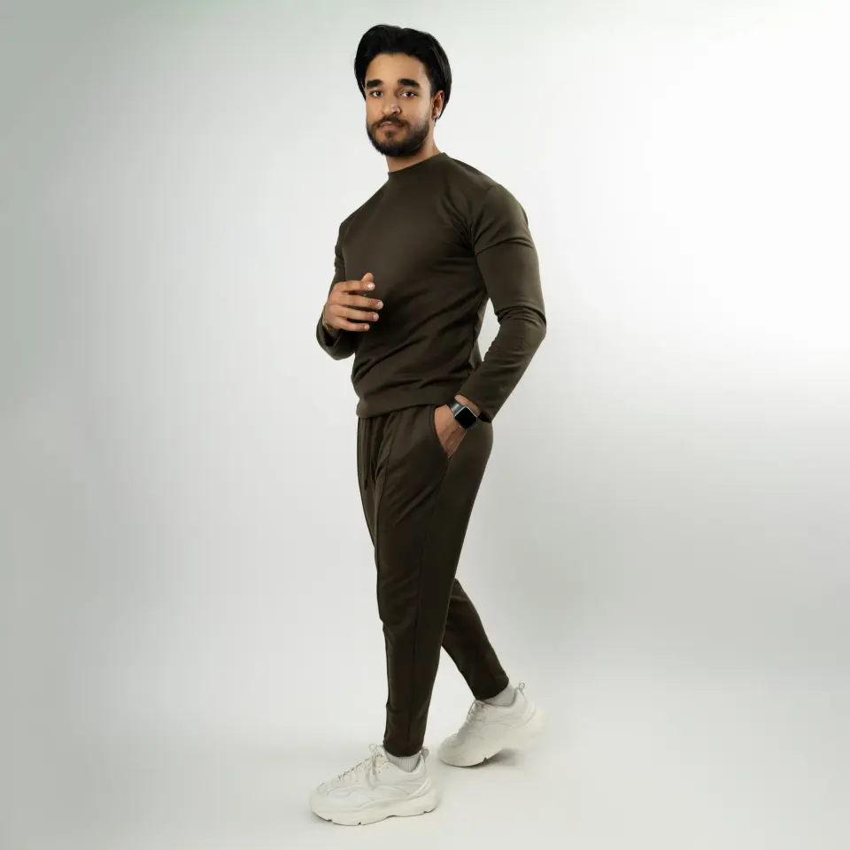 Homme en pull et pantalon de jogging foncés posant sur fond blanc
