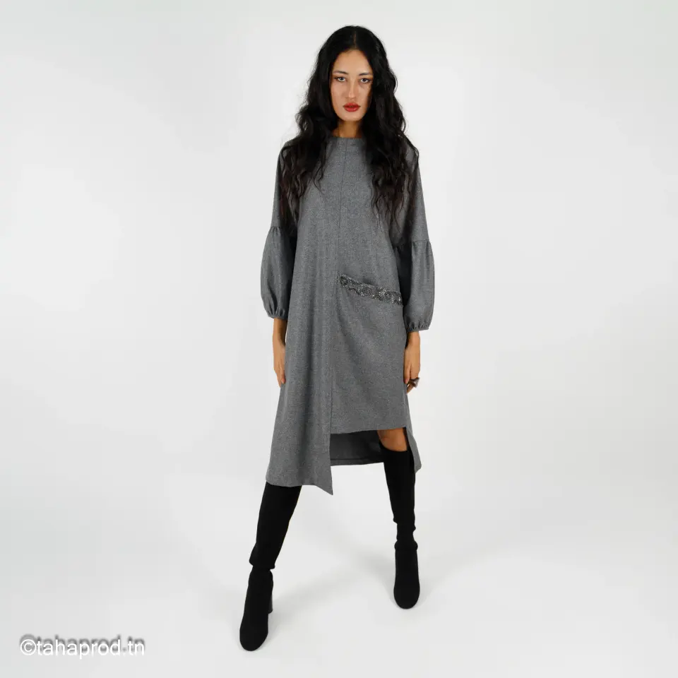 Femme en robe-pull grise et bottes noires, prise de vue mode en studio