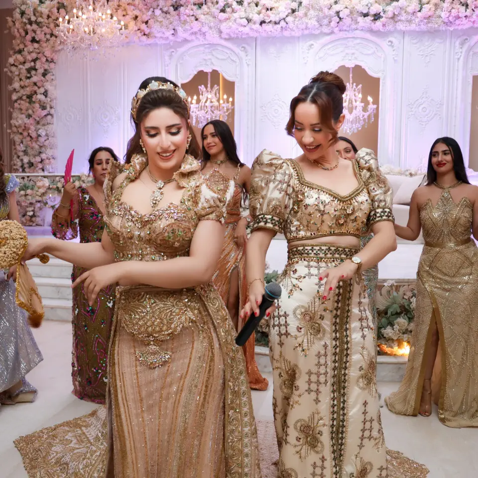 Deux femmes en robes traditionnelles brodées d'or dansant lors d'une réception de mariage
